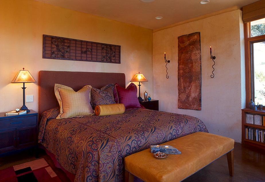The exterior wall at the right of the master bedroom is PISE with no treatment. The other walls are plaster with integral color veneer plaster to maintain the warm tone and organic look. Karen made the screen that hangs above the headboard from recycled materials.